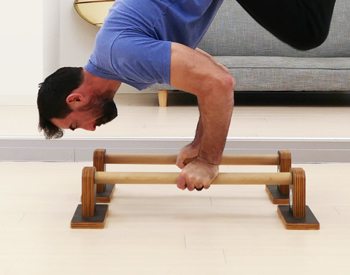 Demonstrating a handstand push up on parallettes